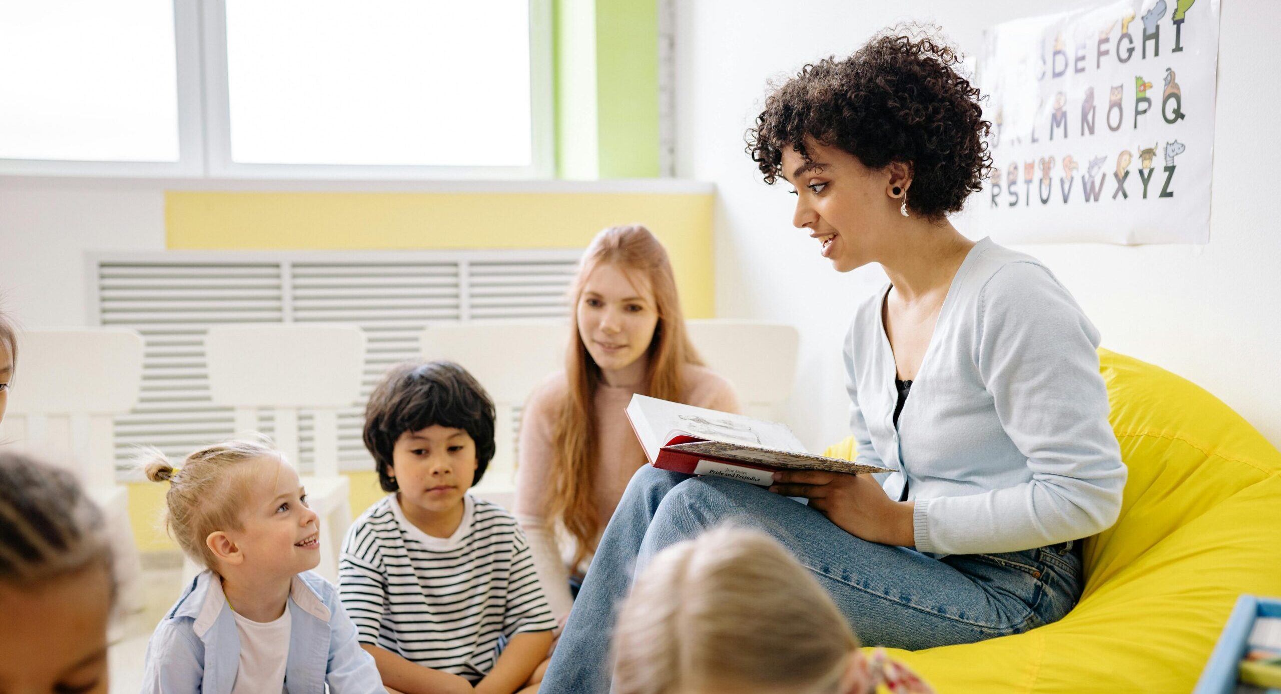 Teacher reading to preschool kids in a colorful classroom setting.